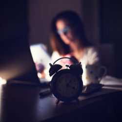 Webdesign für Frauen -Wecker im Vordergrund und Frau arbeitet im Hintergrund Webdesign für Selbstständige und Unternehmer