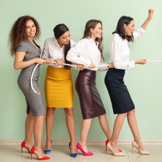 Vier Frauen in femininer Kleidung ziehen an einem Strang Webdesign für selbständige Frauen
